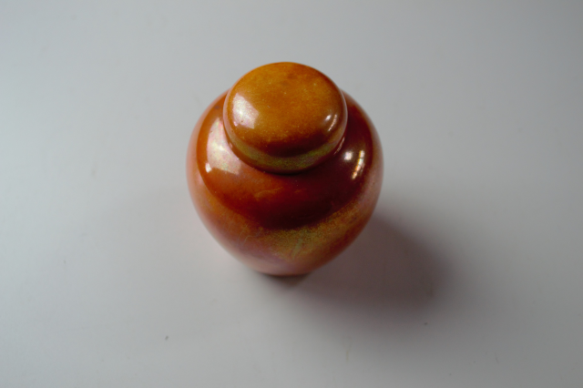 Discover our 1913 Ruskin pottery orange lustre ginger jar. Just 9cm high and 7cm wide. Add this exquisite piece to your collection today!