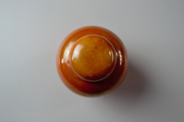 Discover our 1913 Ruskin pottery orange lustre ginger jar. Just 9cm high and 7cm wide. Add this exquisite piece to your collection today!