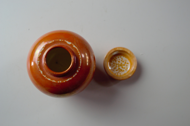 Discover our 1913 Ruskin pottery orange lustre ginger jar. Just 9cm high and 7cm wide. Add this exquisite piece to your collection today!