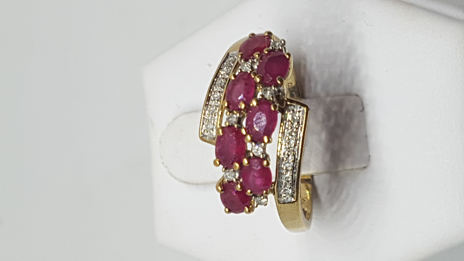 Discover our stunning 9 ct yellow gold ring, featuring 6 oval cut rubies accented by diamonds. Perfect gift with a size T fit. Shop now!
