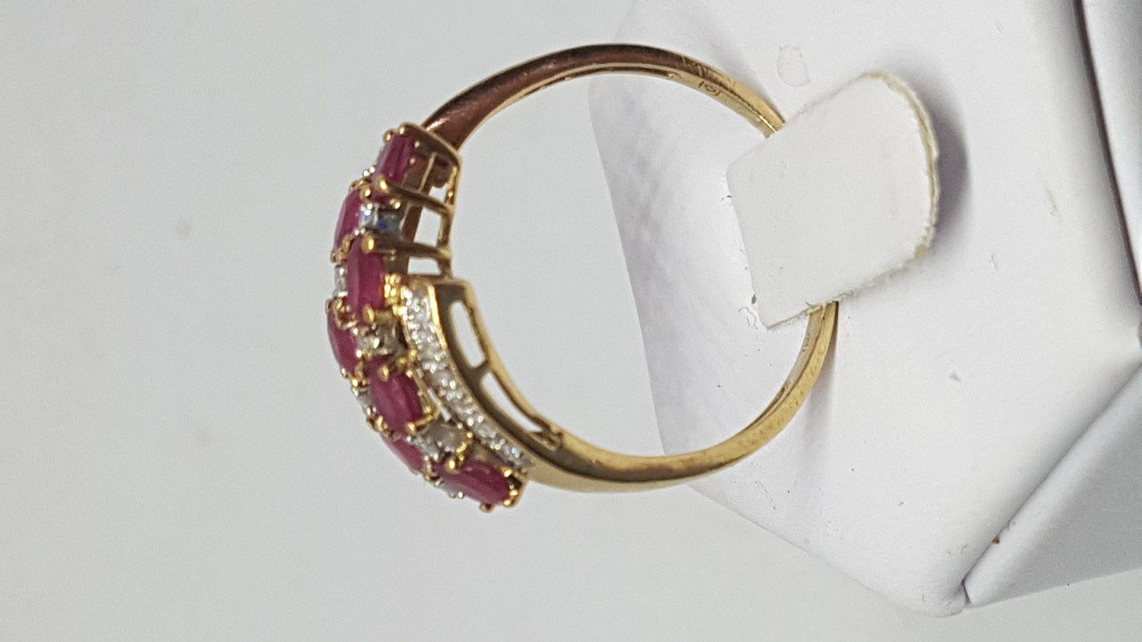 Discover our stunning 9 ct yellow gold ring, featuring 6 oval cut rubies accented by diamonds. Perfect gift with a size T fit. Shop now!
